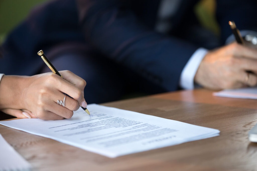 Close up view of woman and man signing document contract