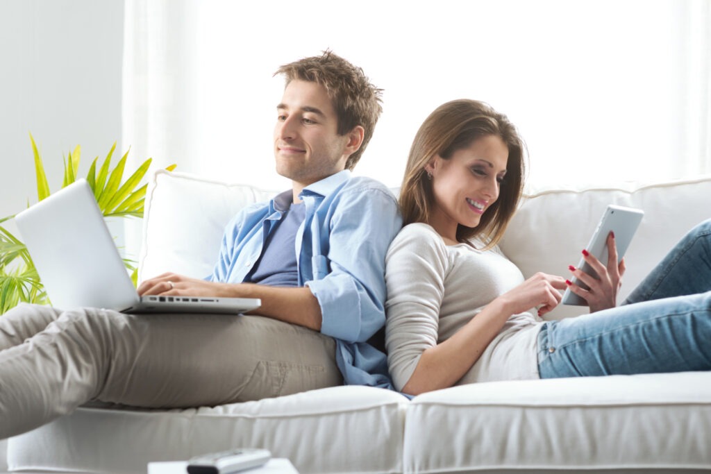 Couple on the couch on devices cohabitation vs. marriage
